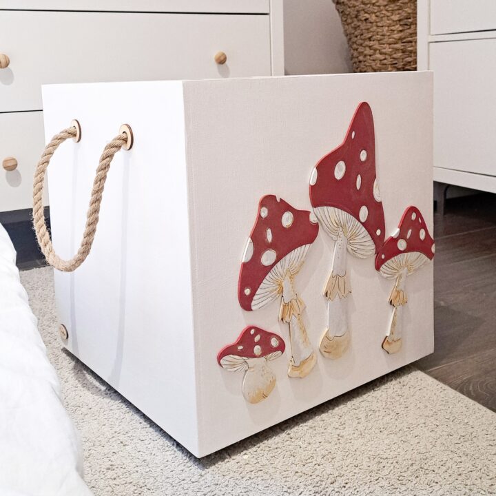 drewniana skrzynia na zabawki z dekorem w muchomorki, skrzynia na w pokoju dziecka ma kółeczka i gruby sznurek by łatwo ją przestawiać